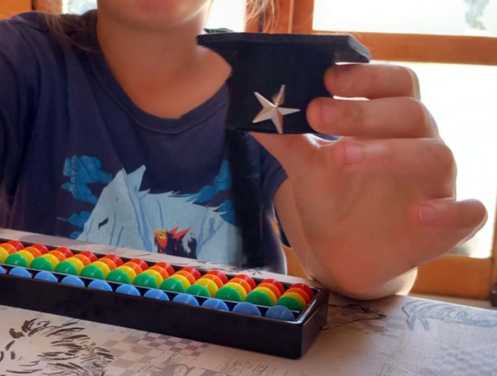 Enfant de l'Imaginarium (Donnezac- 33820 Gironde) qui tient dans sa main une récompense obtenue : pin's des petits as du soroban 